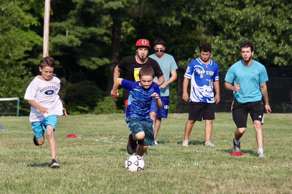 Older boys and counselor coaching younger boys soccer