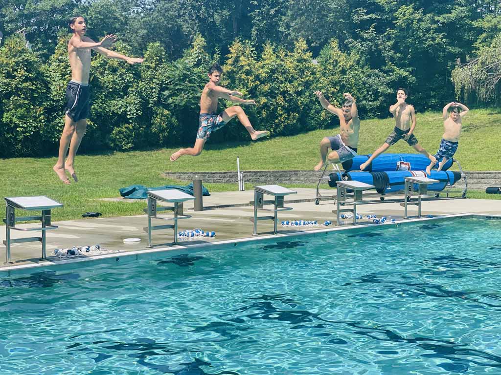 Kids strike a pose in mid air jumping in the pool